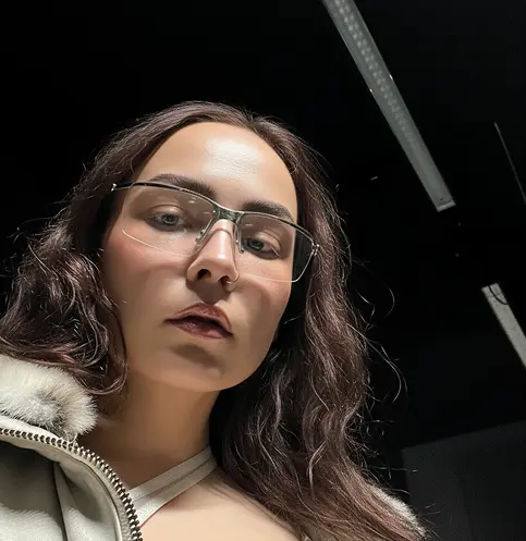 A pixelated image of an orange and white cat lying down, looking to the side, with blurred greenery in the background