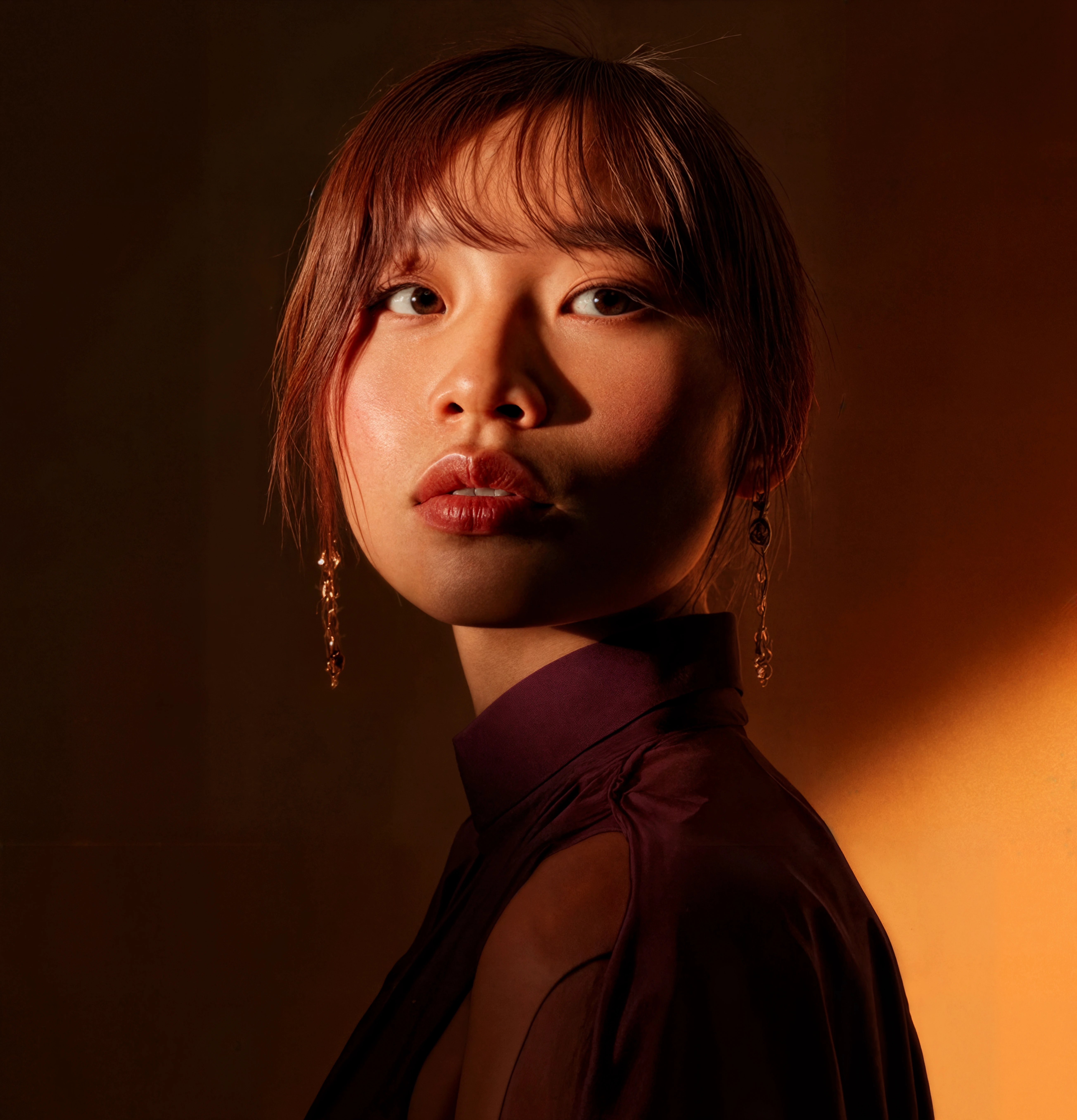 A pixelated image of an orange and white cat lying down, looking to the side, with blurred greenery in the background